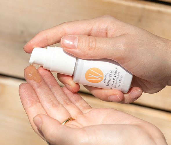 Hands holding a bottle of Brighten Vitamin C Face Serum