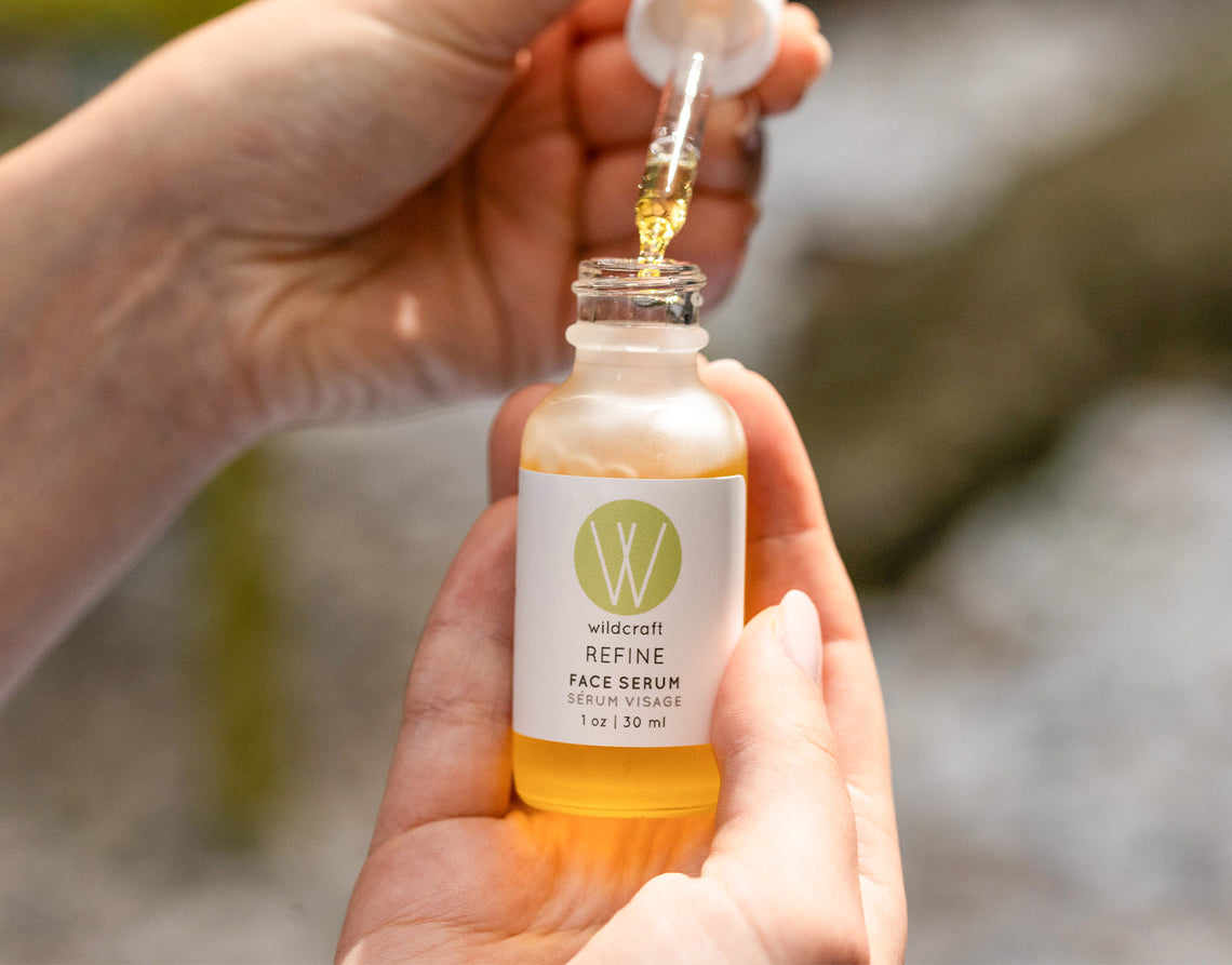 Hands holding a bottle of Refine Face Serum.
