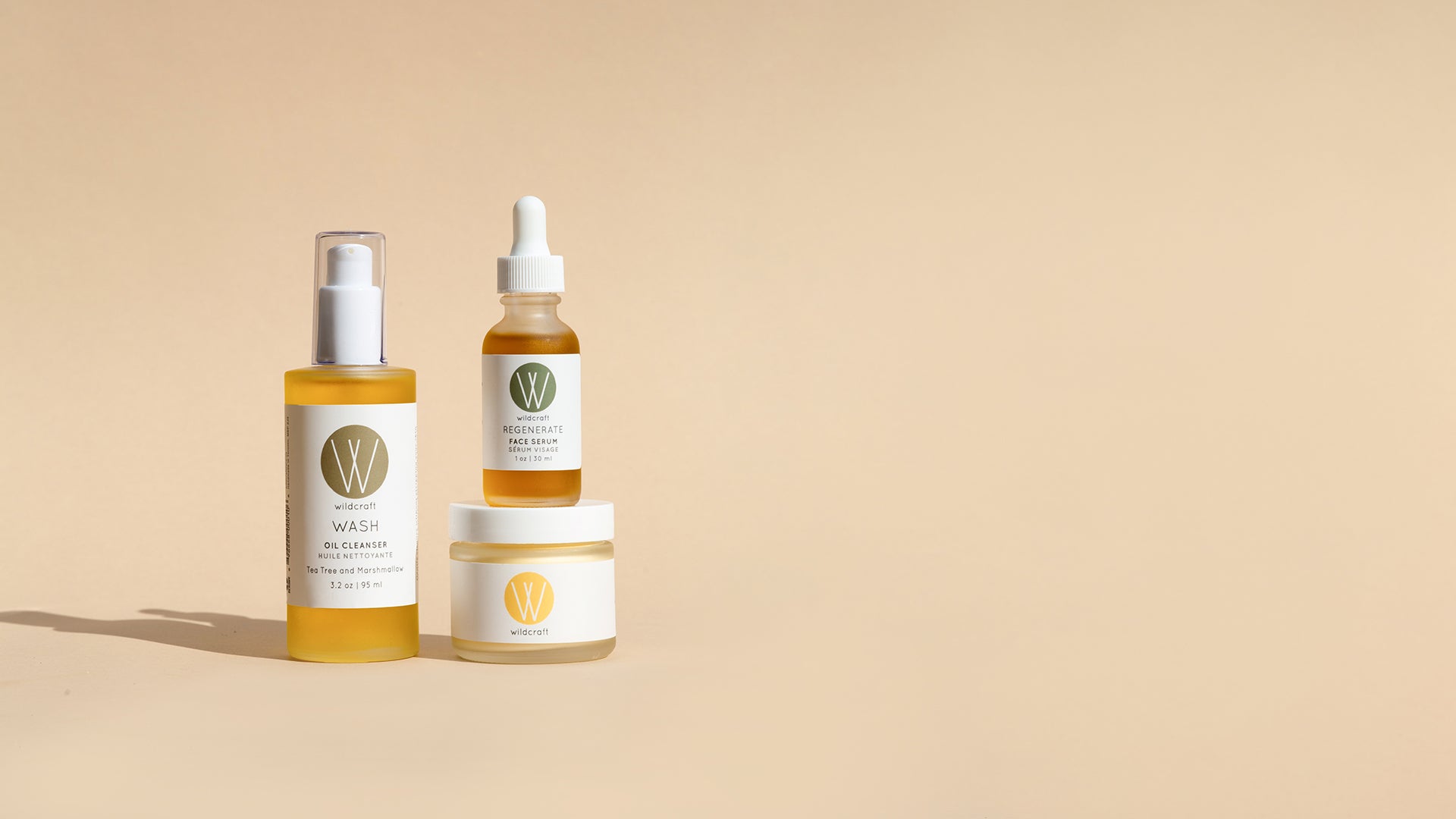 Wildcraft oil cleanser, face serum, and face cream skincare products stacked on top of each other on light backdrop